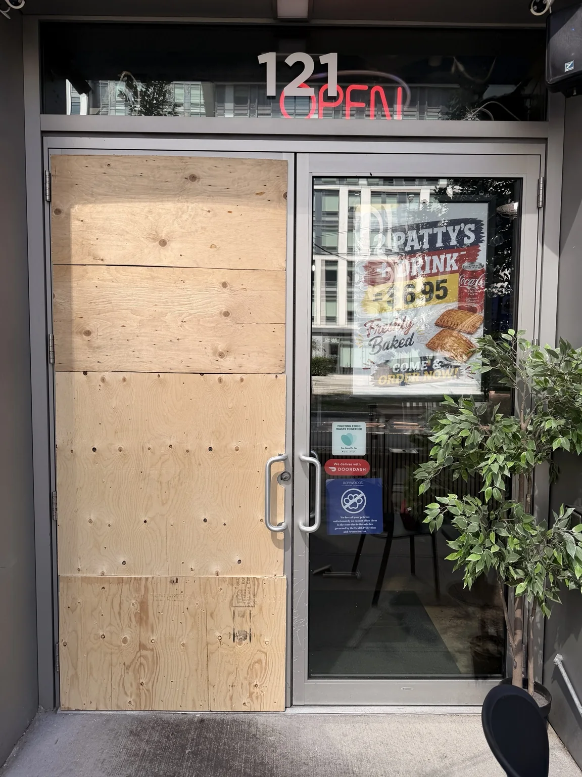 Commercial entry door secured with plywood board-up on Fort York Boulevard